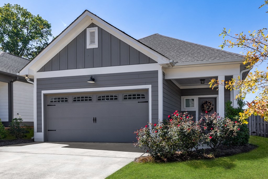 A grey house with a white garage door and a small window above it.