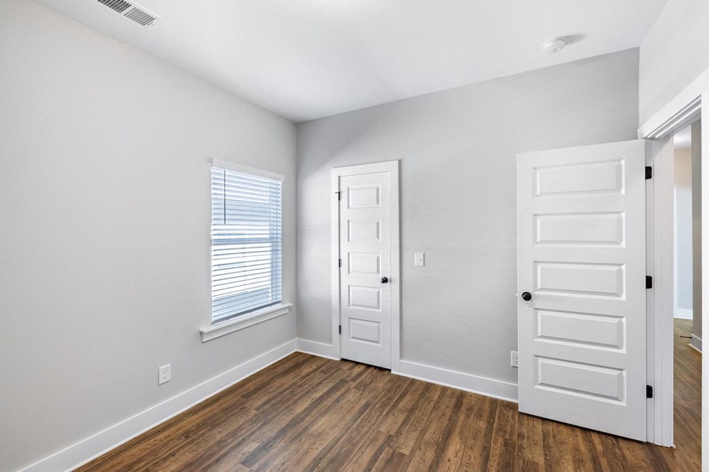 A room with two doors and a window with blinds.