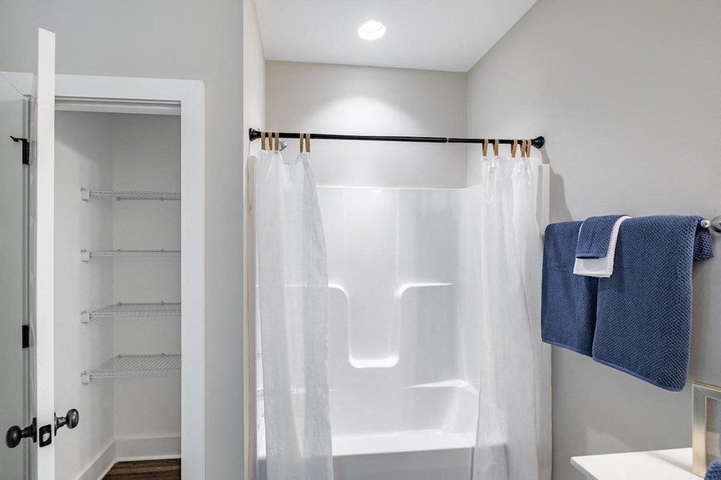 A white bathroom with a white tub and a white shower curtain.