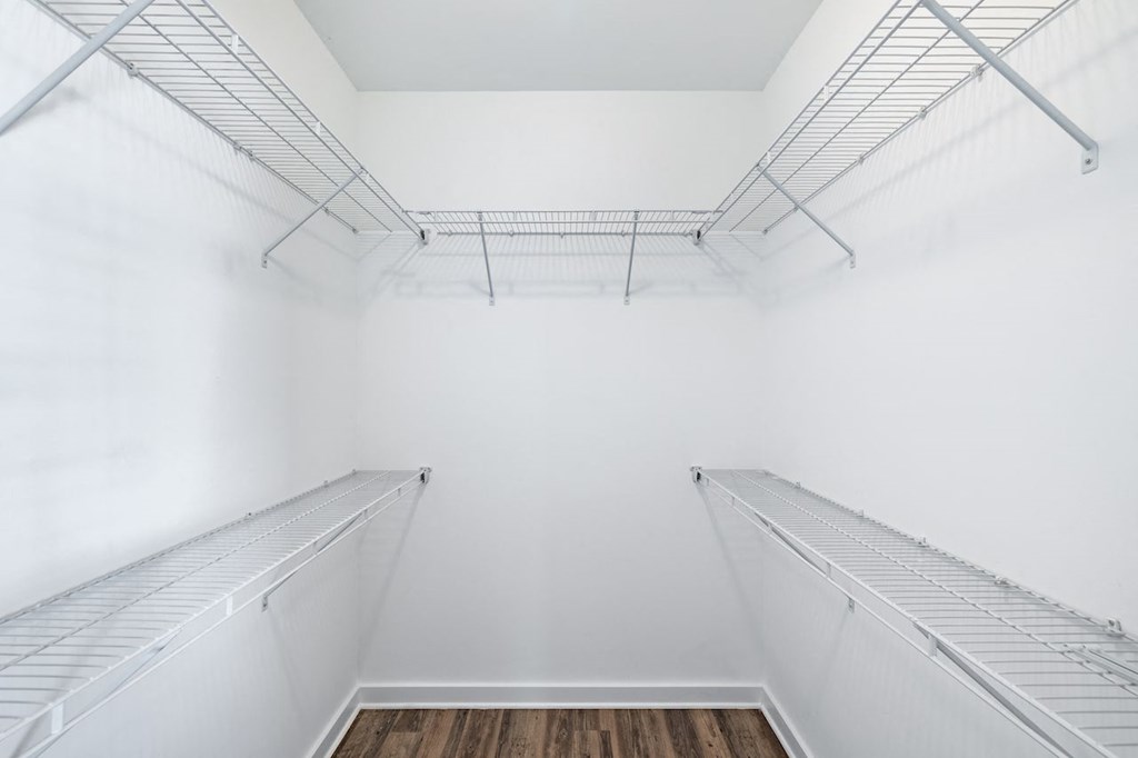 A white empty walk in fridge with a wooden floor.