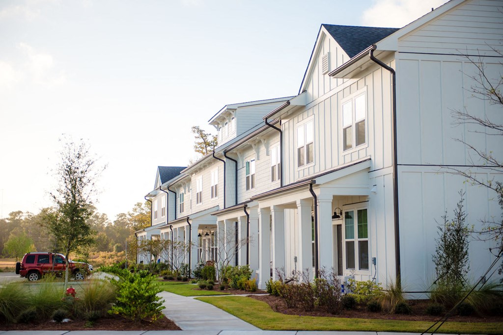 a row of townhomes with a red truck parked in the driveway