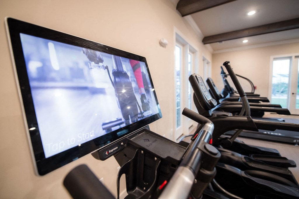 a room filled with cardio equipment and a flat screen tv