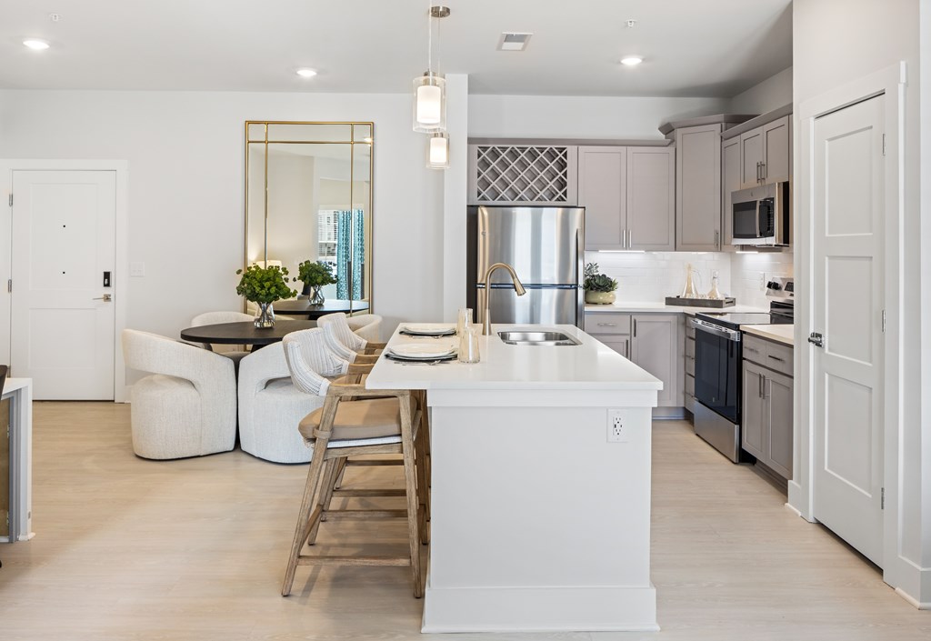 A modern kitchen with a large island and a dining area at Parker Apartments in Raleigh, NC.
