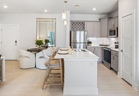 A modern kitchen with a large island and a dining area at Parker Apartments in Raleigh, NC.