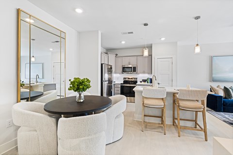 A modern kitchen with a dining table and chairs at Parker Apartments in Raleigh, NC.