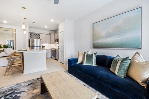 A modern living room with a blue couch and a painting on the wall.
