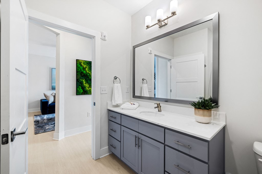 A bathroom with a white countertop and a large mirror at Parker Apartments in Raleigh, NC.