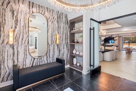 A black and white marbled wall with a mirror and lights above it at Parker Apartments in Raleigh, NC.