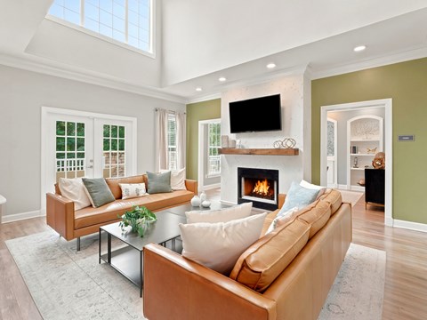 A living room with a fireplace and a television on the wall.