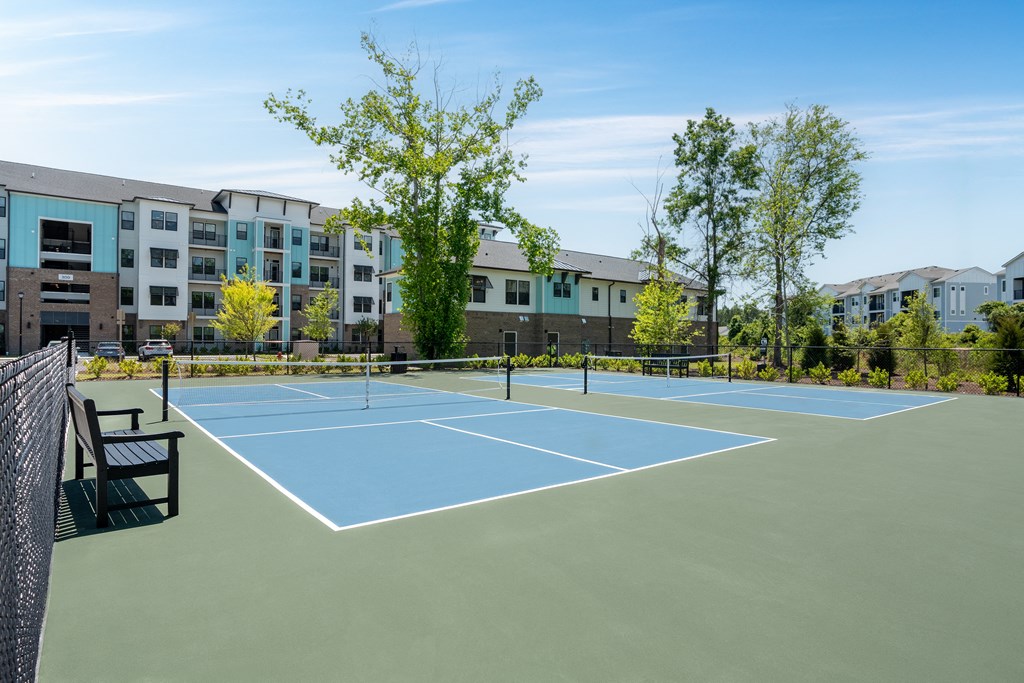 an outdoor tennis court with apartments in the background