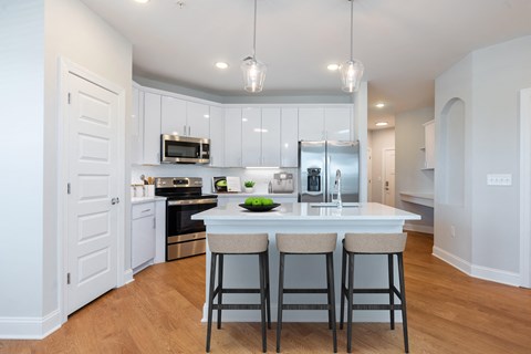 a kitchen with white cabinets and a large island with three stools