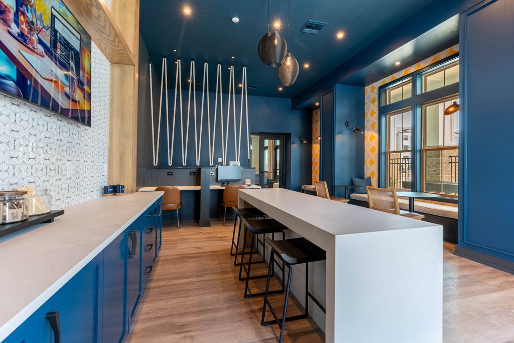 a communal table in a restaurant with blue walls and a long bar with chairs