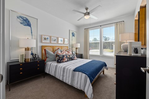 A bedroom with a bed, nightstands, and a ceiling fan.