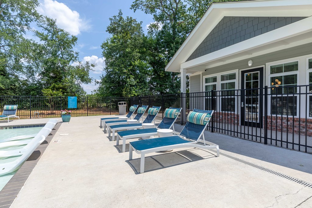 a pool with lounge chairs next to a house