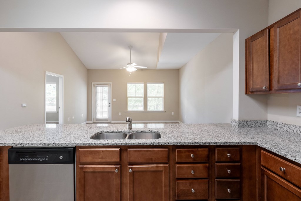 an empty kitchen with granite counter tops and wooden cabinets