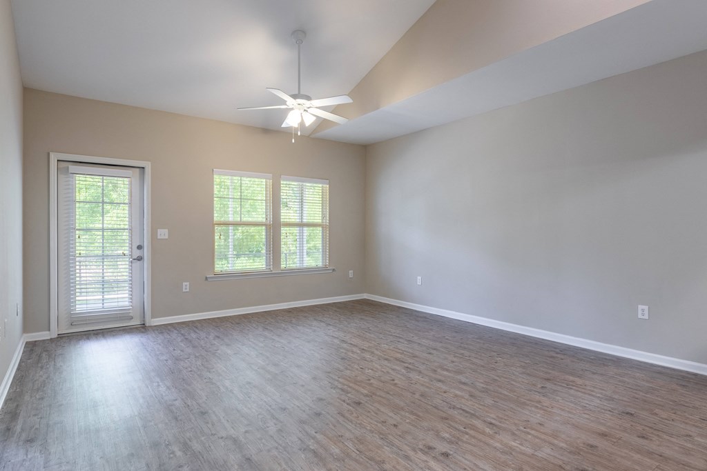 an empty living room with wood floors and a ceiling fan