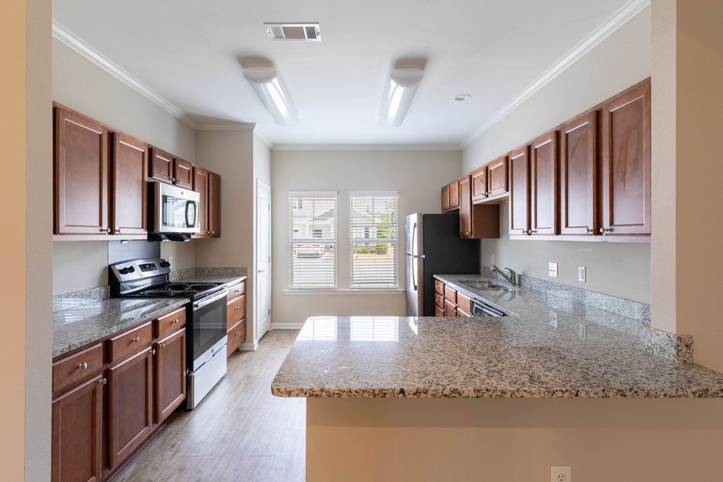 an empty kitchen with granite counter tops and wooden cabinets