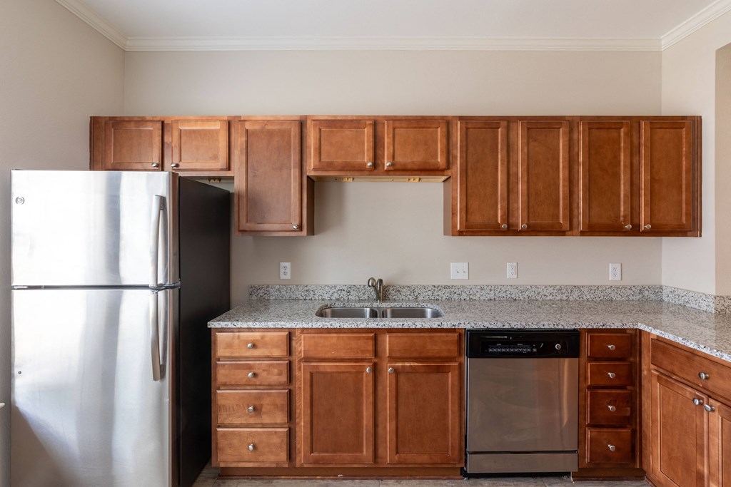 an empty kitchen with wooden cabinets and a stainless steel refrigerator
