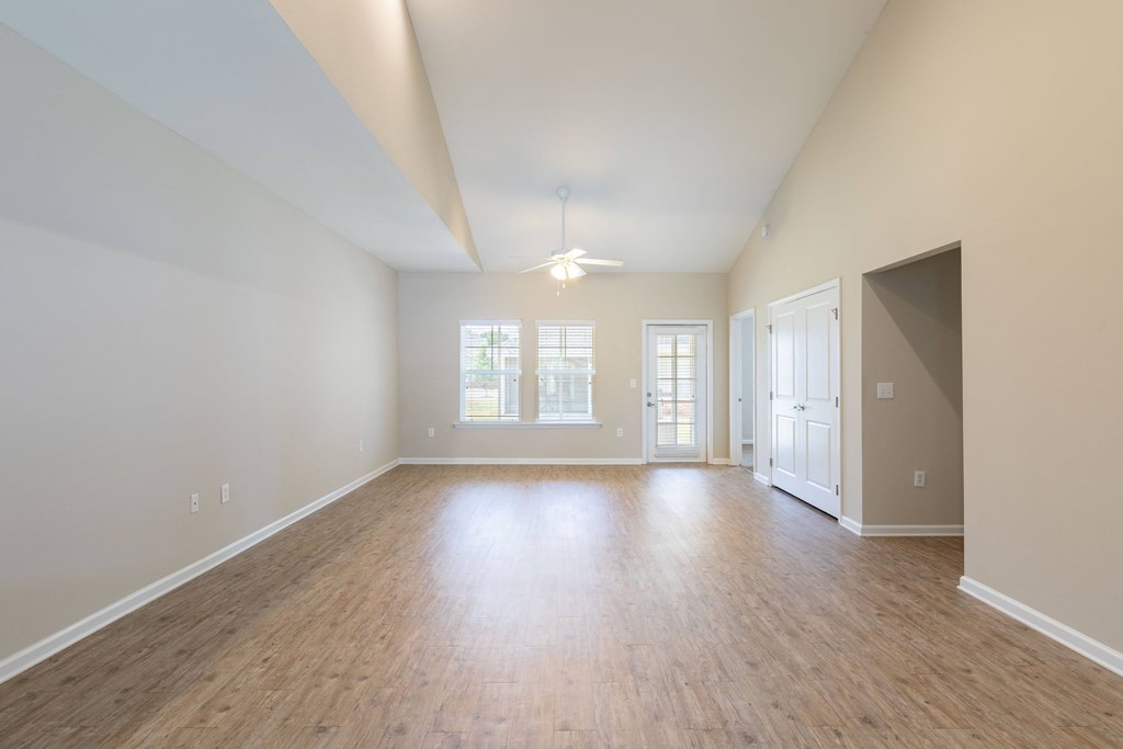 an empty living room with a hard wood floor and white walls
