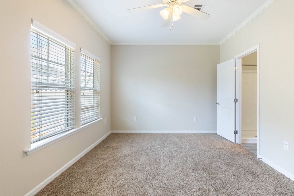 an empty room with a large window and a ceiling fan