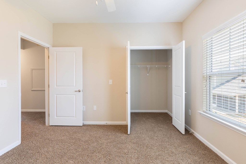 an empty bedroom with a closet and a window