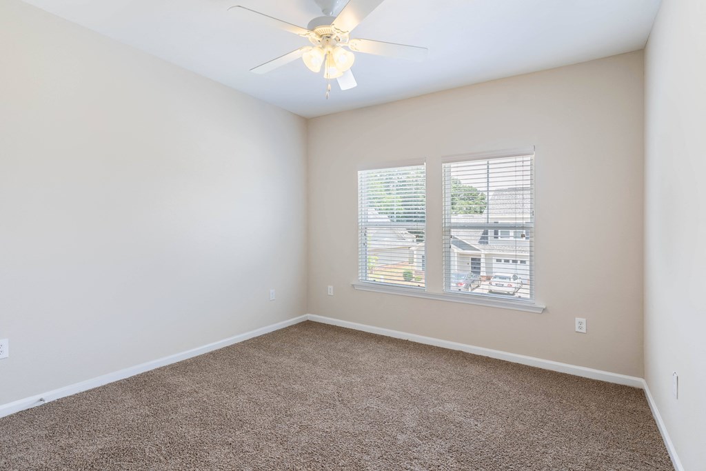 an empty bedroom with a ceiling fan and a window