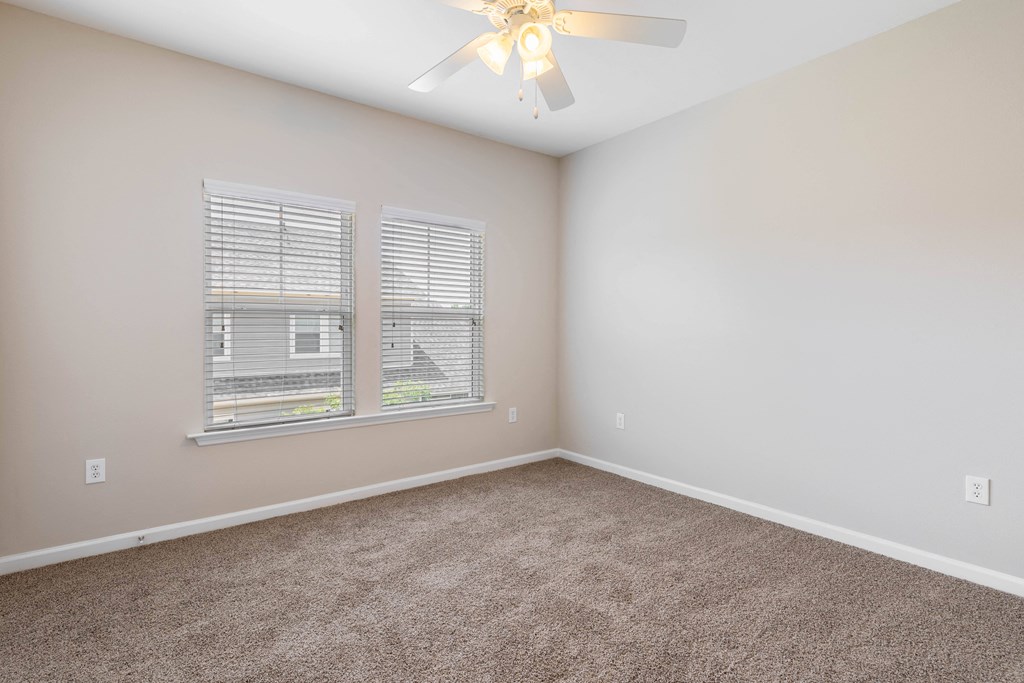 an empty bedroom with a ceiling fan and a window