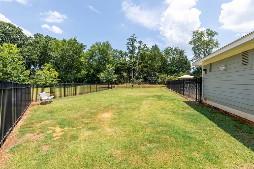 the backyard is fenced in and has a lawn and a fence