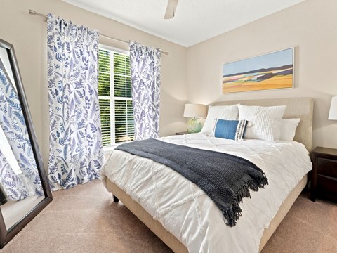 A bedroom with a large bed and a painting of a beach scene on the wall.