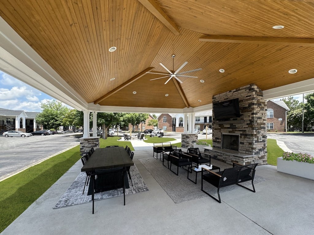 a covered patio with a table and chairs and a fireplace
