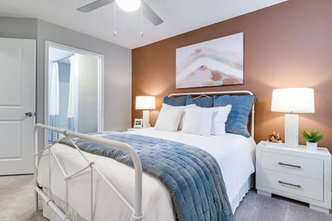 A bedroom with a white bed and a white nightstands