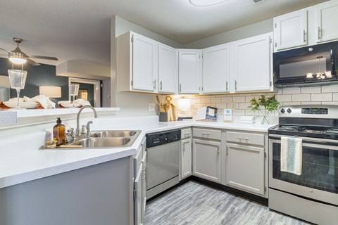 A kitchen with white cabinets and a stainless steel sink.