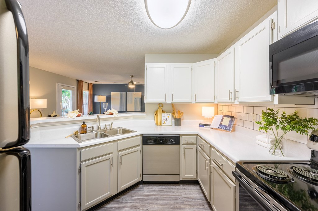 an empty kitchen with white cabinets and appliances and a sink