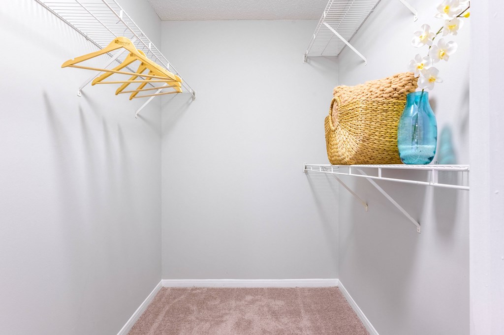 a closet with white walls and white shelves and a basket hanging on the wall