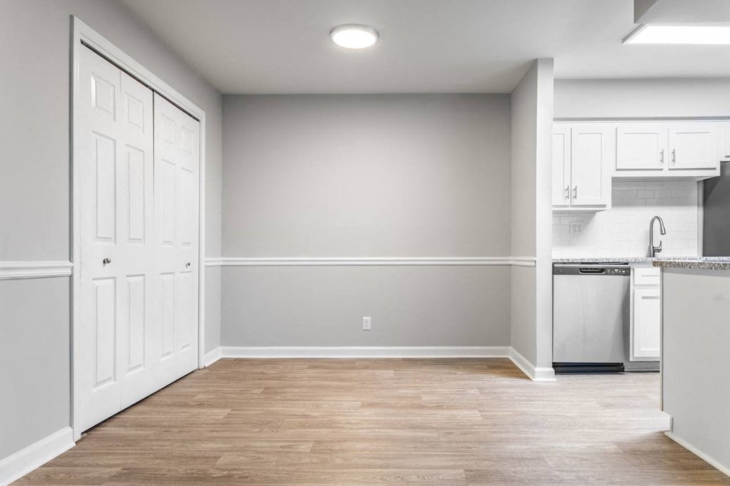 a bedroom with a medium sized bed and a kitchen with white cabinets and stainless steel appliances