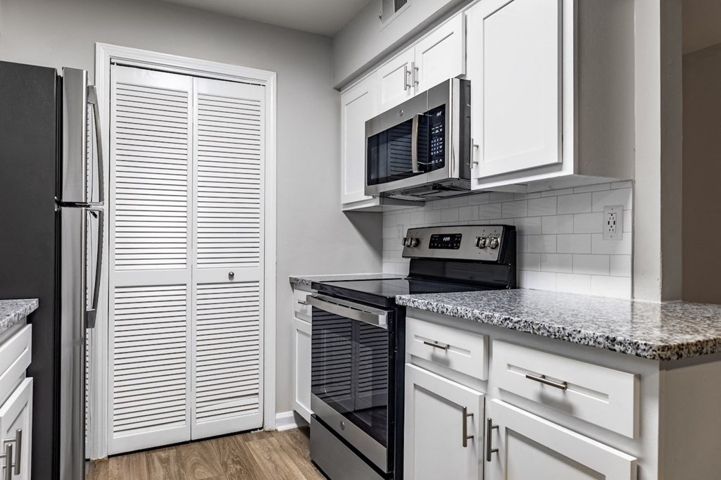 a kitchen with white cabinets and black appliances