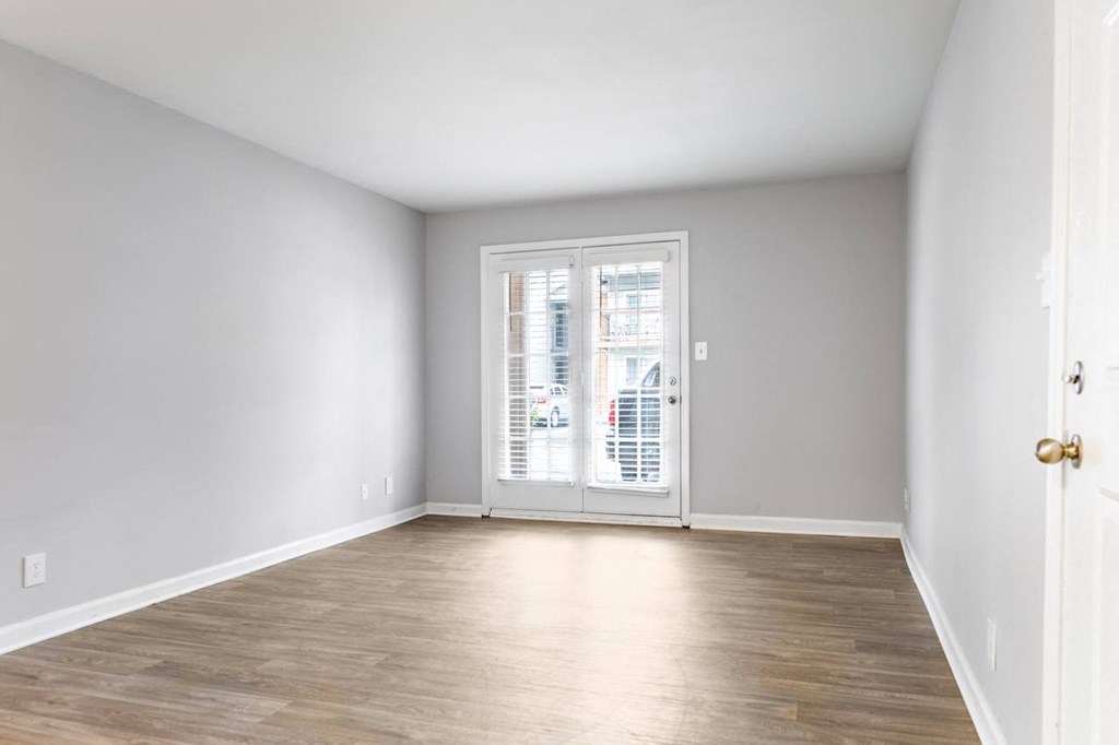 a bedroom with a hardwood floor and a door that leads to a balcony