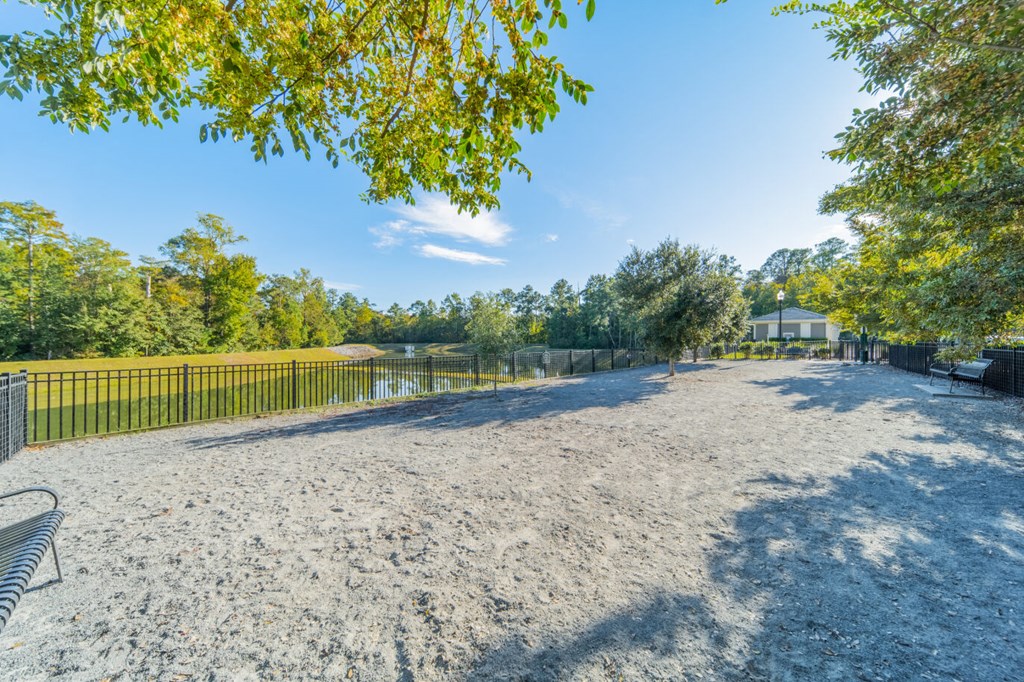 a large sandy beach next to a fence and a body of water