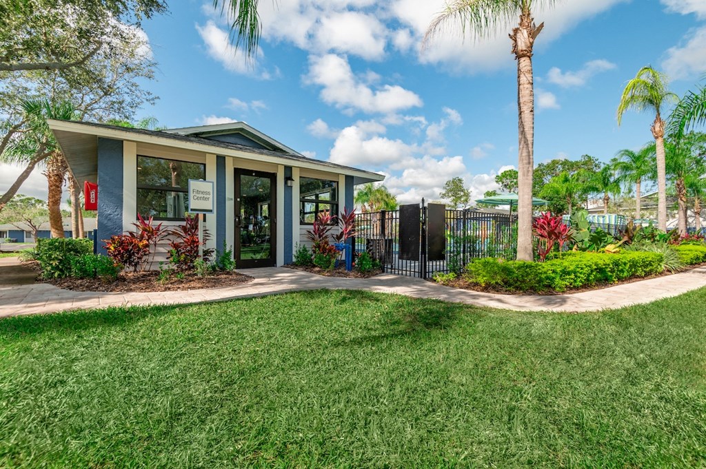 a house with a fenced in yard with grass and palm trees