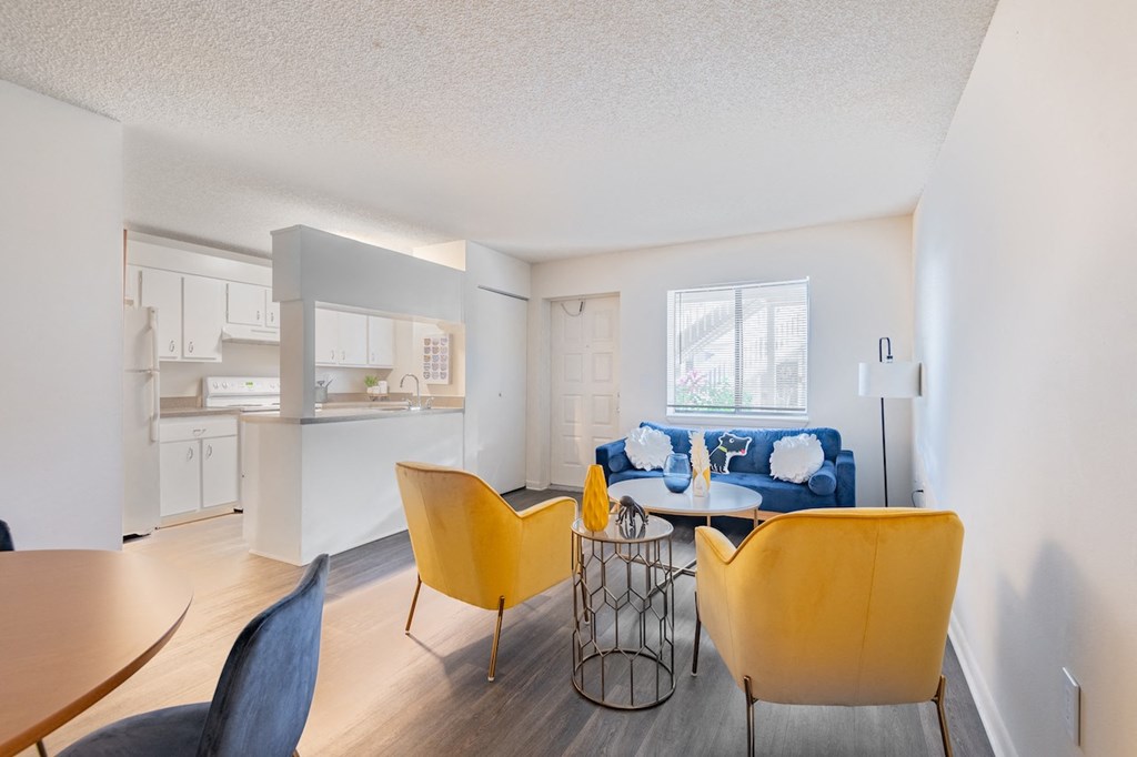 a living room and kitchen with yellow chairs and a table