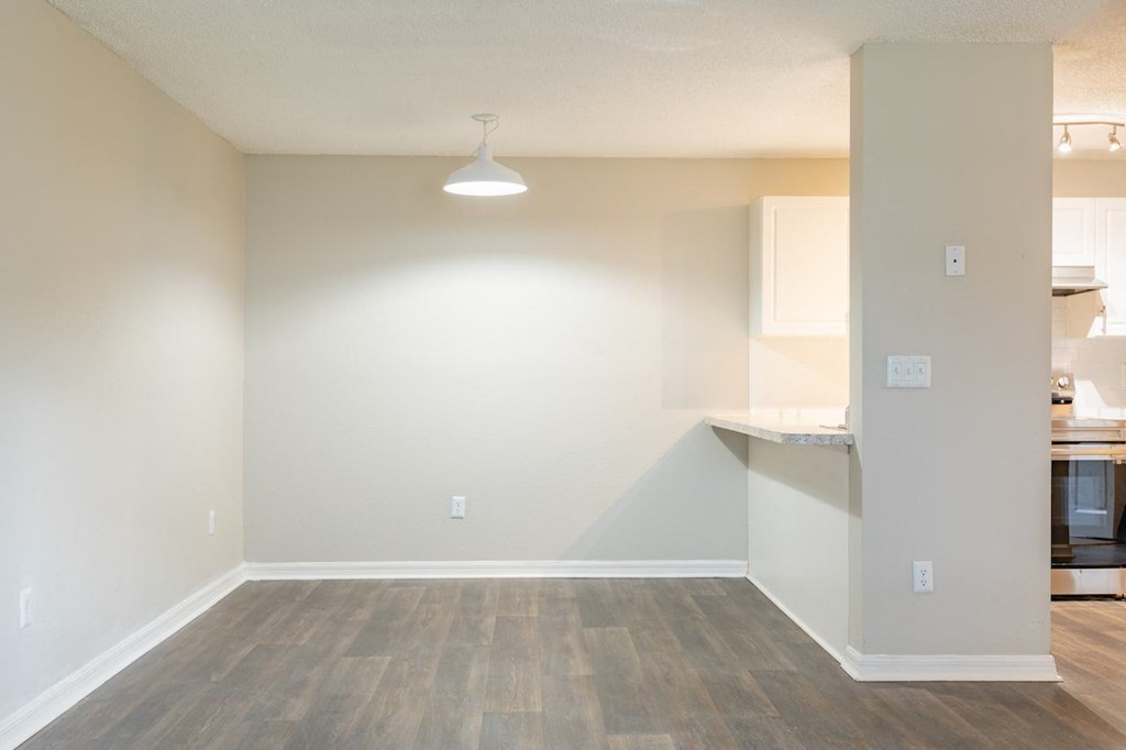 an empty living room and kitchen with a hard wood floor