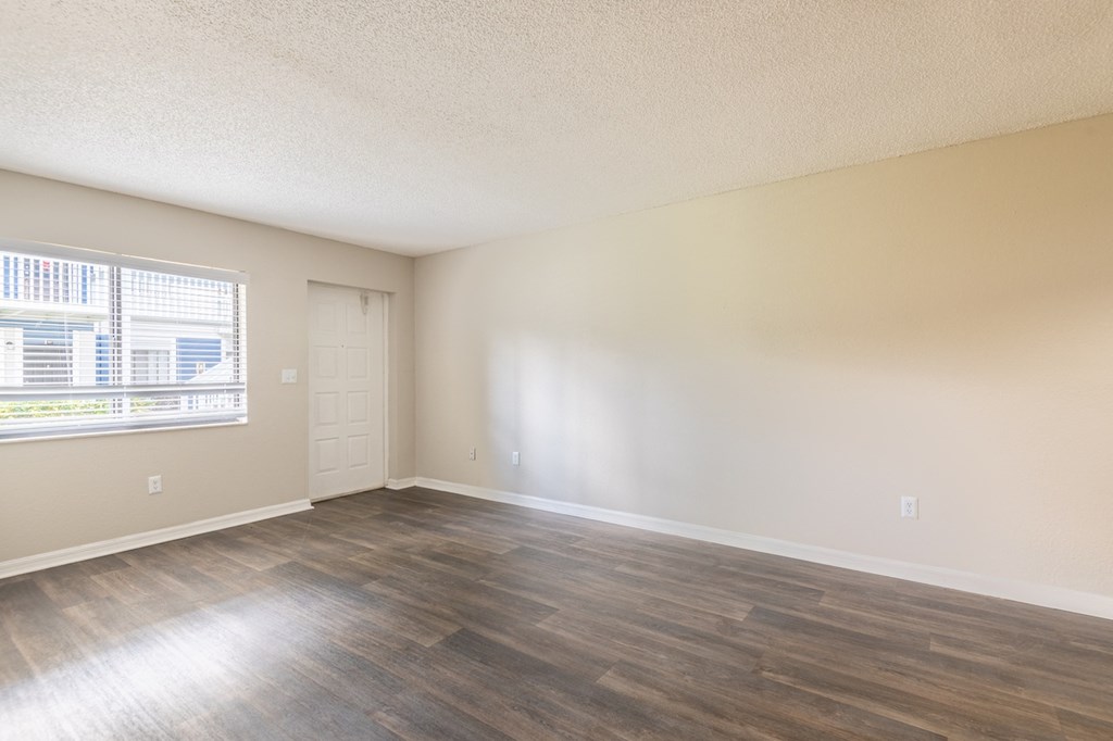 an empty living room with wood flooring and a window
