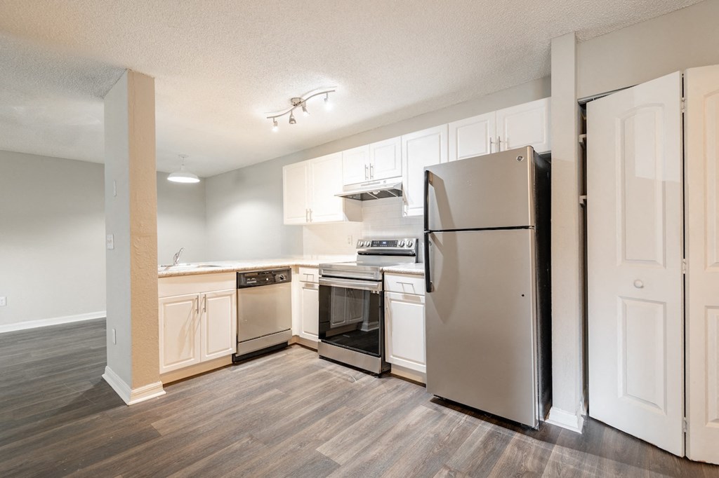 an empty kitchen with white cabinets and stainless steel appliances