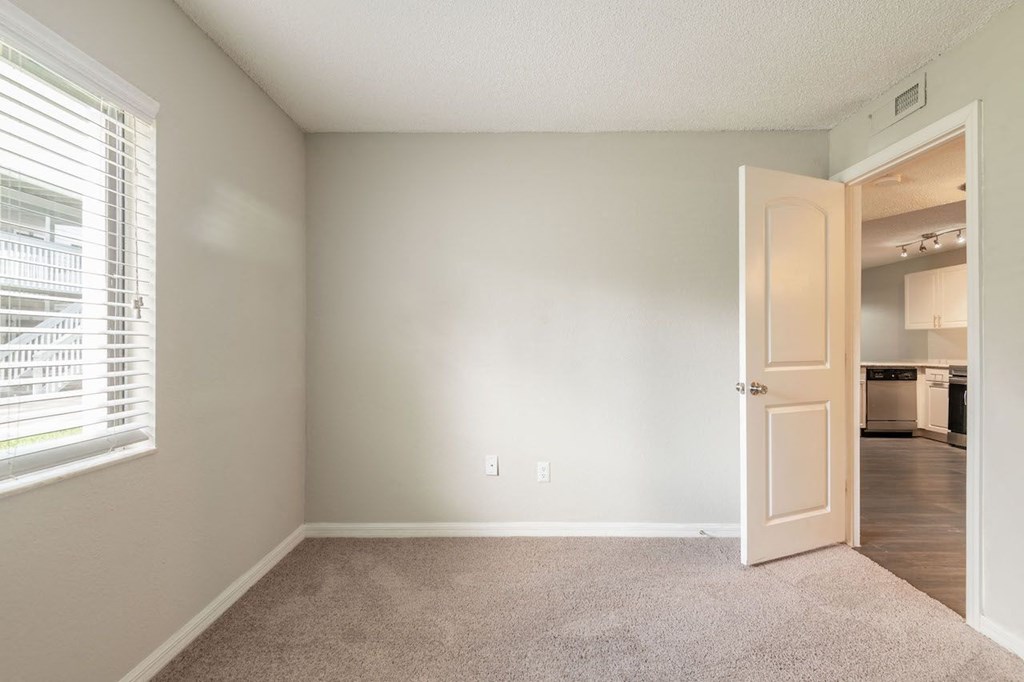 an empty living room with an open door to a kitchen