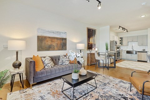 A living room with a grey couch and a large painting on the wall.
