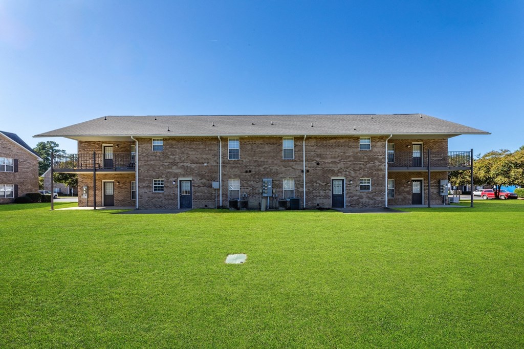 A large building with a flat roof and a green lawn in front.