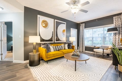 a living room with a yellow couch and a ceiling fan