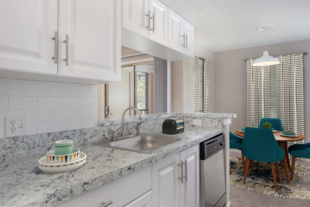 a kitchen with white cabinets and a sink and a table with chairs