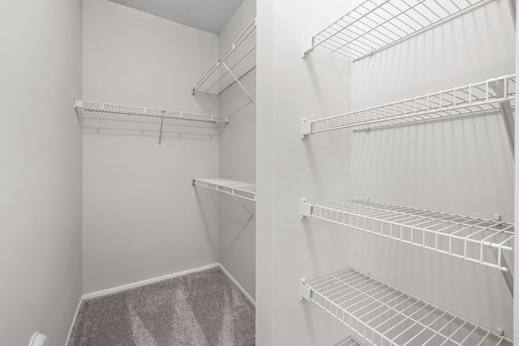 two views of a walk in closet with white walls and shelves