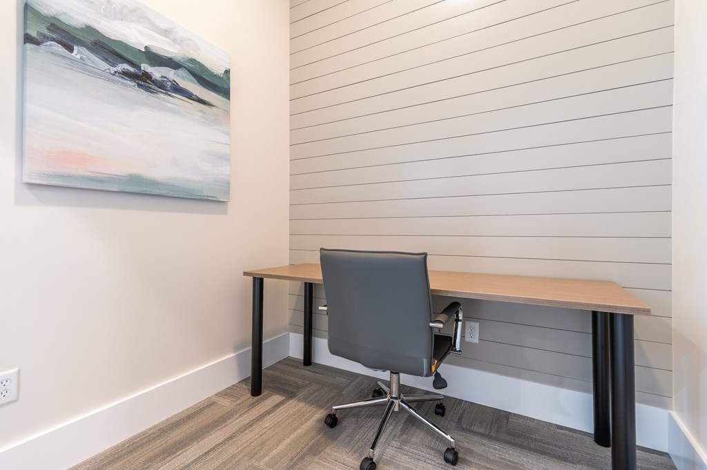 A grey office chair sits in front of a wooden desk.
